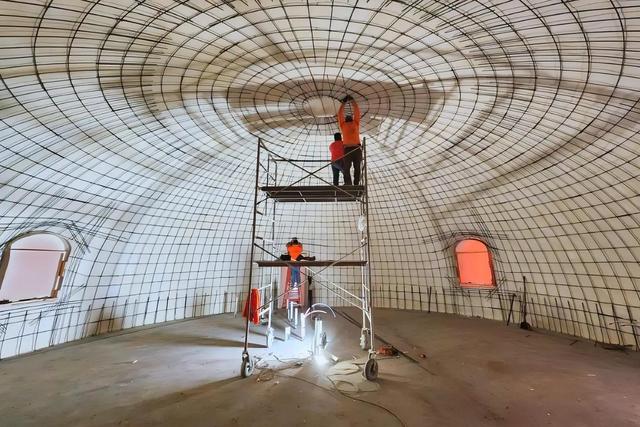 Crews tie rebar at the top of the dome